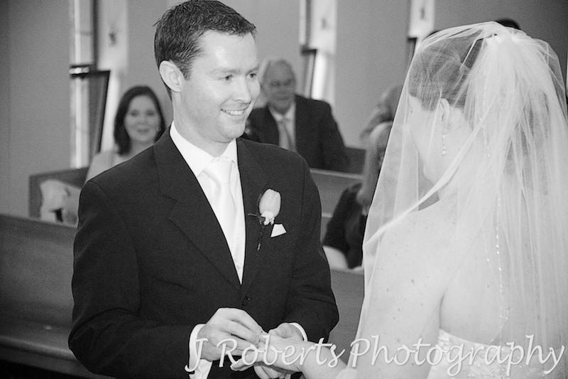 Groom putting the ring on the brides finger - wedding photography sydney